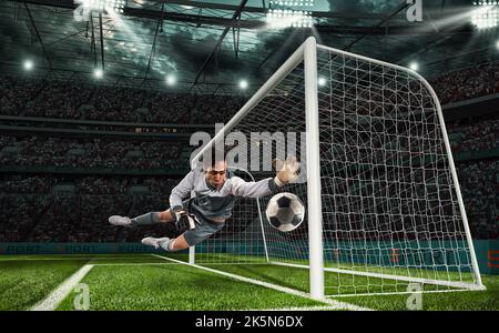 Soccer goalkeeper that makes a great save and avoids a goal during a match at the stadium Stock Photo