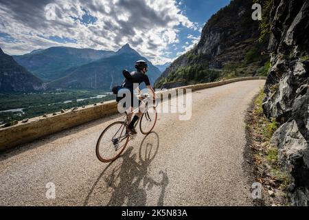 Male road cyclist riding up the balcony road from Bourg d'Oisans to Villard Notre Dame, French Alps. Stock Photo