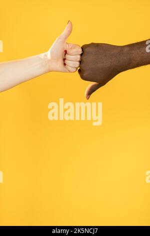 Like dislike gesture. Cultural diversity. Yes no opposition. Different feedback. man white woman multiracial hands with thumbs up down isolated on ora Stock Photo