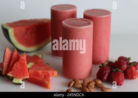 Watermelon strawberry smoothie. Summer drink made of watermelon and fresh strawberries in almond milk. Shot on white background along with watermelon Stock Photo