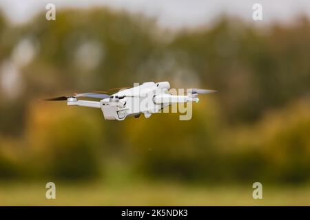 A flying camera drone with spinning rotors exposed outdoors as UAV Stock Photo