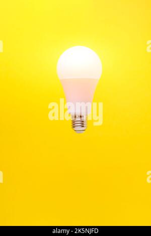 Burning LED eco friendly light bulb on yellow background Stock Photo