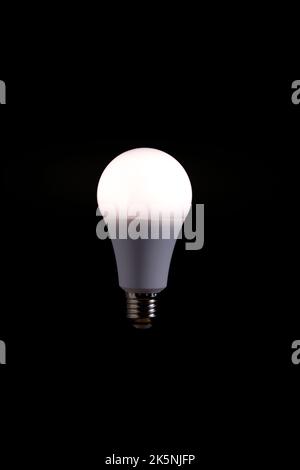 Burning LED eco friendly light bulb on black background Stock Photo