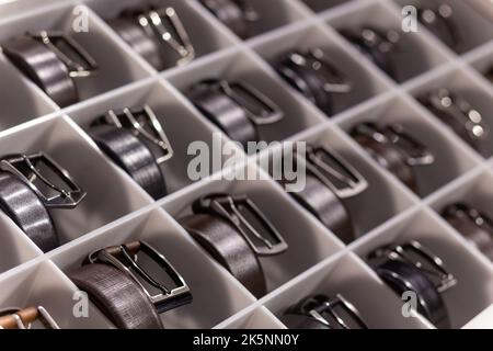 Various coloured leather belt display on shelf in the store in a men clothing boutique. Small depth of field. Fashion and clothing concept Stock Photo