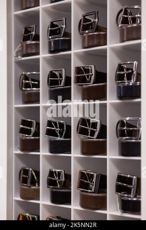 Various coloured leather belt display on shelf in the store in a men clothing boutique. Small depth of field. Fashion and clothing concept Stock Photo