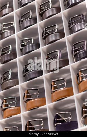 Various coloured leather belt display on shelf in the store in a men clothing boutique. Small depth of field. Fashion and clothing concept Stock Photo