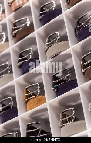 Various coloured leather belt display on shelf in the store in a men clothing boutique. Small depth of field. Fashion and clothing concept Stock Photo