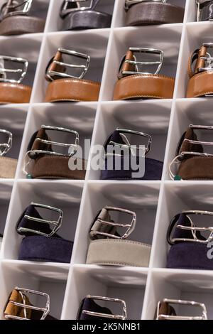 Various coloured leather belt display on shelf in the store in a men clothing boutique. Small depth of field. Fashion and clothing concept Stock Photo