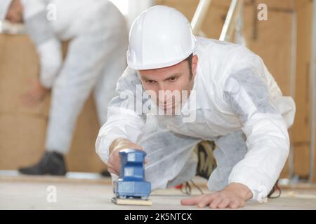 builder using sander on floor Stock Photo