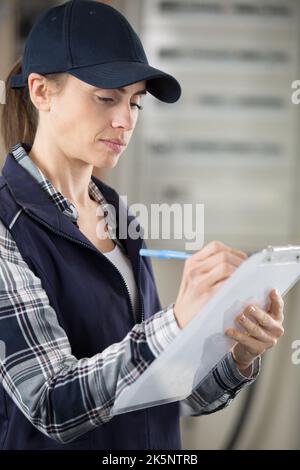 female contractor writing on clipboard Stock Photo