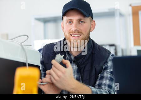young male technician checking refrigerator with screwdriver Stock Photo