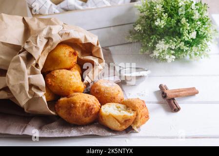 Cottage cheese round doughnuts pile with powdered sugar in a paper bag. Whole dough balls without holes. Stock Photo