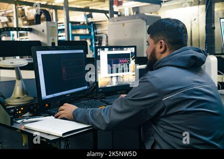 Perm, Russia - September 21, 2022: operator controls the industrial machine while sitting in front of the monitors Stock Photo
