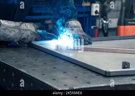welder at work, welding metal parts in workshop Stock Photo