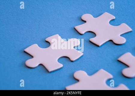 White jigsaw puzzle pieces on blue background with limited close up focus. Stock Photo