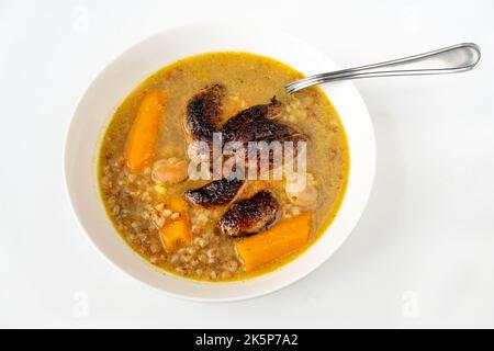 Rabbit soup with fried liver and kidney, boiled carrot and buckwheat in white plate on white background. Stock Photo