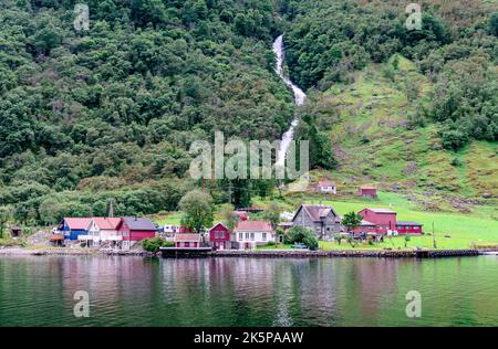 The picturesque hamlet of Tufto and the Tuftofossen (the waterfall) on the shores of the Naeroyfjord, in Vestland County, Norway. Stock Photo