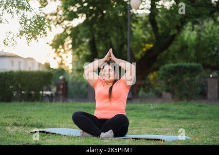 park yoga meditation practice overweight woman Stock Photo