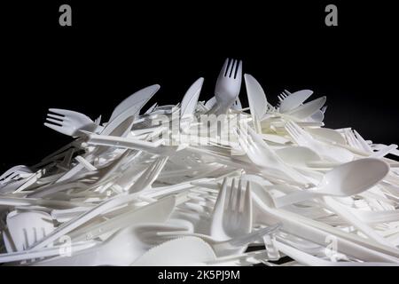 Pile of single use plastic knives, forks and spoons cutlery. Stock Photo
