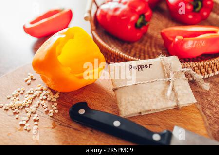 Close up of signed paper package with collected seeds from sweet peppers on table at home. Saving and storing them wrapped in paper. Propagating veget Stock Photo