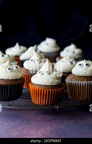 Pumpkin spice cupcakes on a metal cooling rack, against a black background. Stock Photo