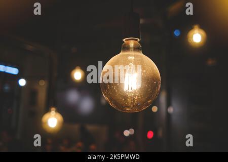 Bulb lighting in the night with bokeh at the background, CloseUp Of Illuminated Light Bulb In Retro Style Stock Photo
