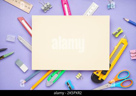 Blank paper sheet with utility knives and stationery on violet background Stock Photo
