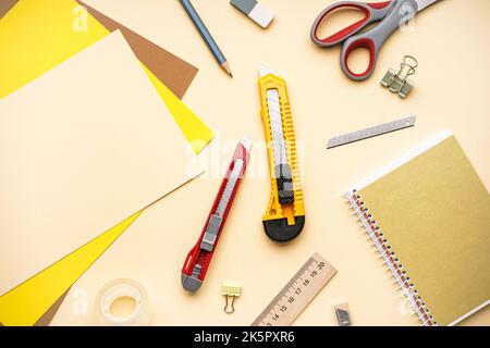 Utility knives with stationery on beige background Stock Photo