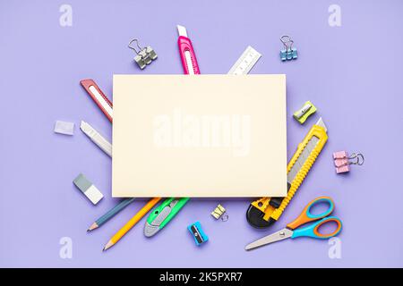 Blank paper sheet with utility knives and stationery on violet background Stock Photo