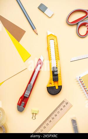 Utility knives with stationery on beige background Stock Photo