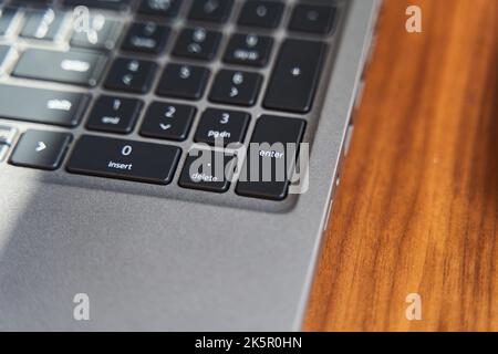 Top view of a part of a gray laptop keyboard on a wooden table Stock Photo