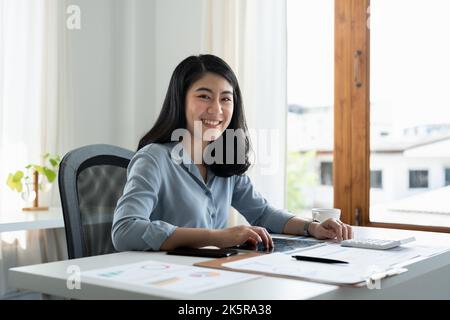 Portrait of attractive entrepreneur asian woman, business woman looking at camera while working for accounting finance with laptop computer. Stock Photo