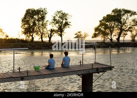 Little boys is fishing at sunset on the lake. Summer leisure Stock Photo