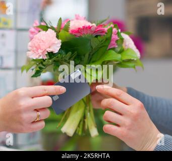 Buying a little beauty. a woman buying flowers with her credit card from a florist. Stock Photo