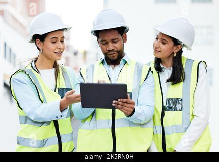 Building, digital tablet and construction worker team collaboration and planning at a site, checking online plan and strategy. Vision, design and Stock Photo