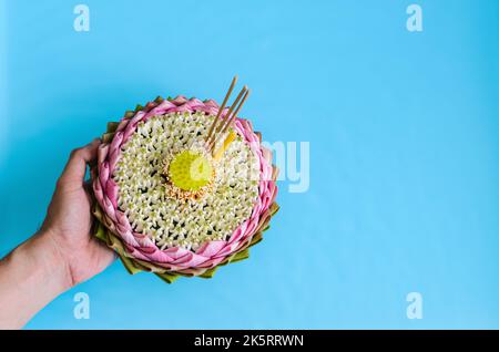 Pink lotus petal krathong decorates with its pollen, crown flower, blurred focus incense stick and candle holding by hand for Thailand Loy Krathong fe Stock Photo
