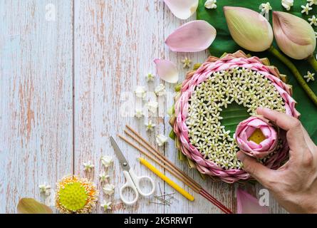 Pink lotus petal krathong for Thailand Loy Krathong festival decorates from lotus, crown flower, incense stick and candle with blurred focus of hand h Stock Photo
