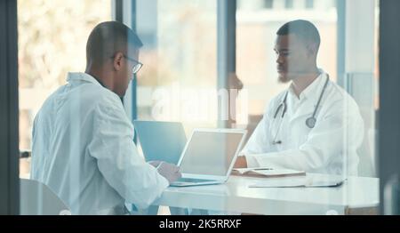Team of medical doctors working together. Two doctors working on their laptops together. Medical colleagues brainstorm and plan during a meeting Stock Photo