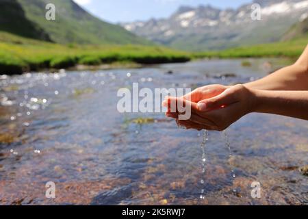 Close up of a woman hands catching water from river in the mountain Stock Photo