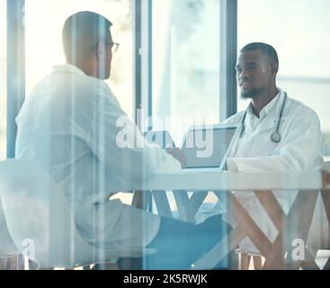 Two doctors talking in a meeting. Colleagues collaborate in a medical meeting in the hospital. Young medical coworkers planning together in a meeting Stock Photo
