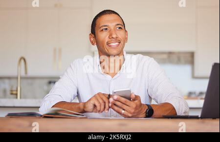Man, smile and phone at table thinking for remote work, communication or trading on internet. Smartphone, businessman and focus for idea in kitchen Stock Photo