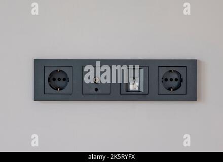 Wall outlet with different sockets. Multi panel, internet, tv or radio adapter socket in smoked color on champagne color wall background at home Stock Photo