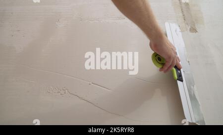 Builder smears a putty knife with a spatula. Worker puts mortar on a construction spatula. Stock Photo