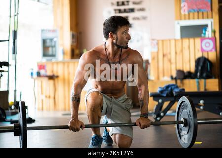 Distracted man resting in a gym while holding a bar with weights Stock Photo