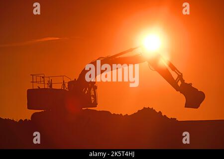 caterpillar digger working on site at sunset united kingdom Stock Photo