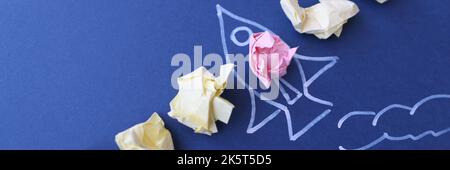 Lot of crumpled papers lying on blue paper with painted rocket Stock Photo