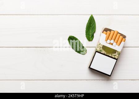 Pack of menthol cigarettes and fresh mint on colored table, Menthol cigarettes top view flat lay. Stock Photo