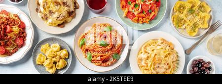 Pasta panorama. Assortment of Italian pastas, with spaghetti in tomato sauce and Bolognese, seafood pasta, penne with chicken, ravioli and others, overhead flat lay shot with wine Stock Photo