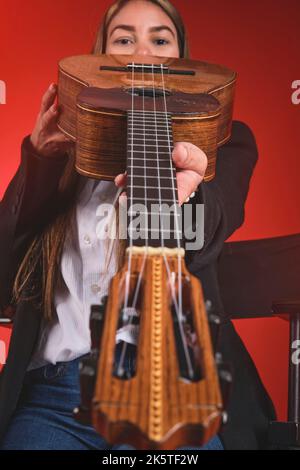 Beautiful young woman playing a CUATRO, typical Venezuelan instrument. Recording session, Concept of music and typical instruments. Stock Photo