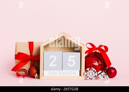 25 december. Christmas composition on colored background with a wooden calendar, with a gift box, toys, bauble copy space. Stock Photo